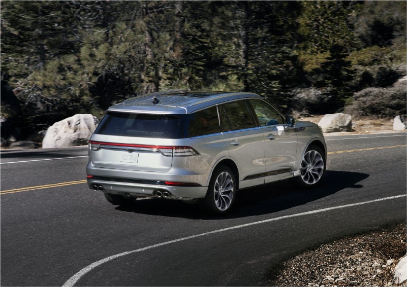 A 2023 Lincoln Aviator® Grand Touring model is shown being driven on a tight turn of a mountain road | Purchase Lincoln in Mayfield KY