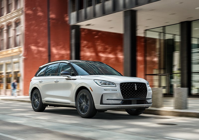 The 2024 Lincoln Corsair® SUV with the Jet Appearance Package and a Pristine White exterior is parked on a city street. | Purchase Lincoln in Mayfield KY
